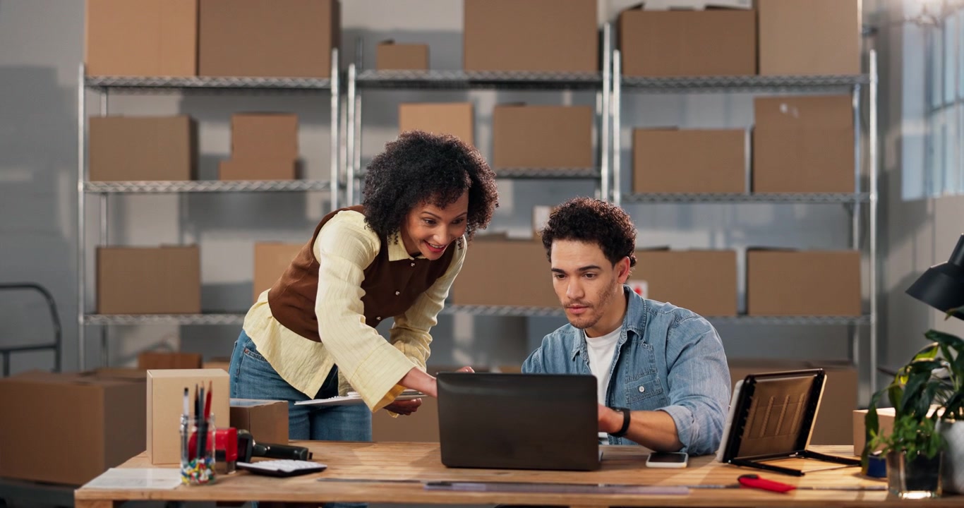 Two Colleagues Collaborating on Laptop in Warehouse Office