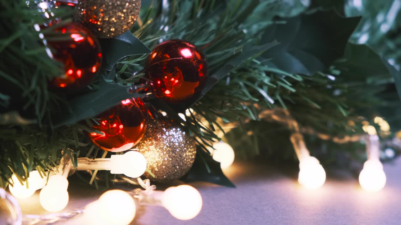 fondo de año nuevo o navidad. primer plano de la rama de abeto artificial decorada con bolas de navidad rojas y doradas y bombillas de guirnaldas intermitentes