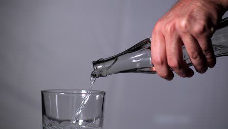 hand holding water bottle and pouring isolated on grey background