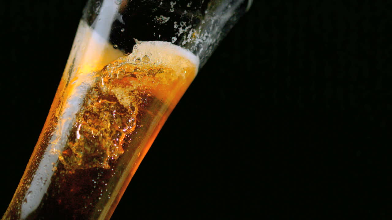 Birra che versa nel bicchiere su sfondo nero