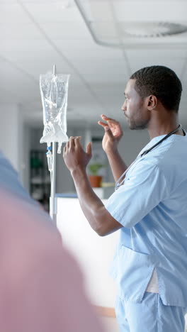 vertical video of african american doctor training trainee doctors, applying drip, slow motion