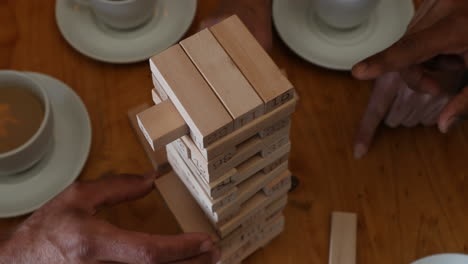 friends playing jenga game on table while having coffee in bar 4k