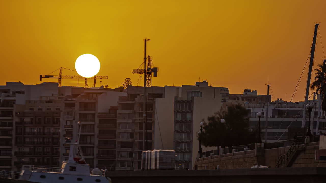 Gzira, Malta durante um pôr do sol dourado - lapso de tempo em telefoto com zoom do anoitecer