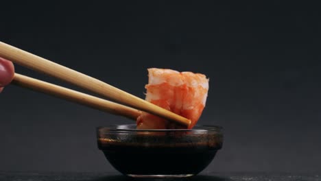 shrimp dipping in sauce with chopsticks