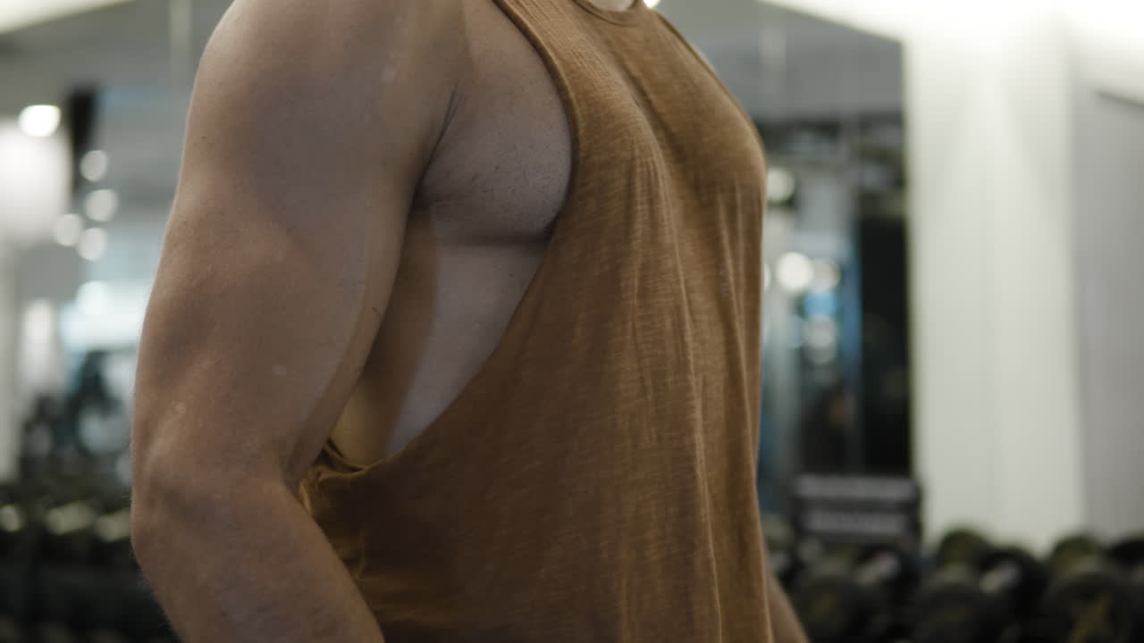 фит-мен поднимает тяжесть, делает молот, бицепс скручивает, упражняется с весом - нажимает вблизи на мышцы, сгибает и прокачивает