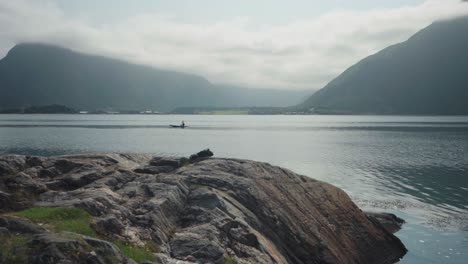 man paddling on the peaceful lake during foggy morning near mardalsfossen in molde, norway