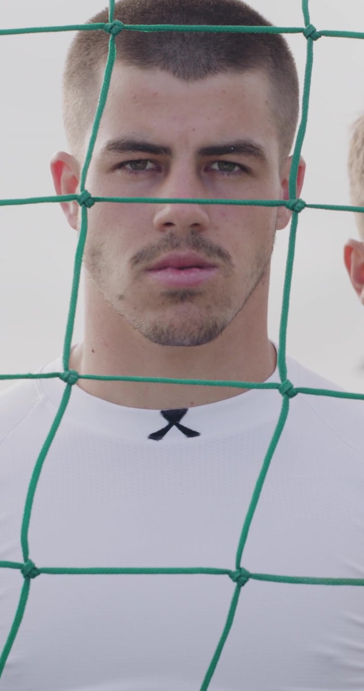 Portrait of a Young Male Soccer Player Behind a Goal Net
