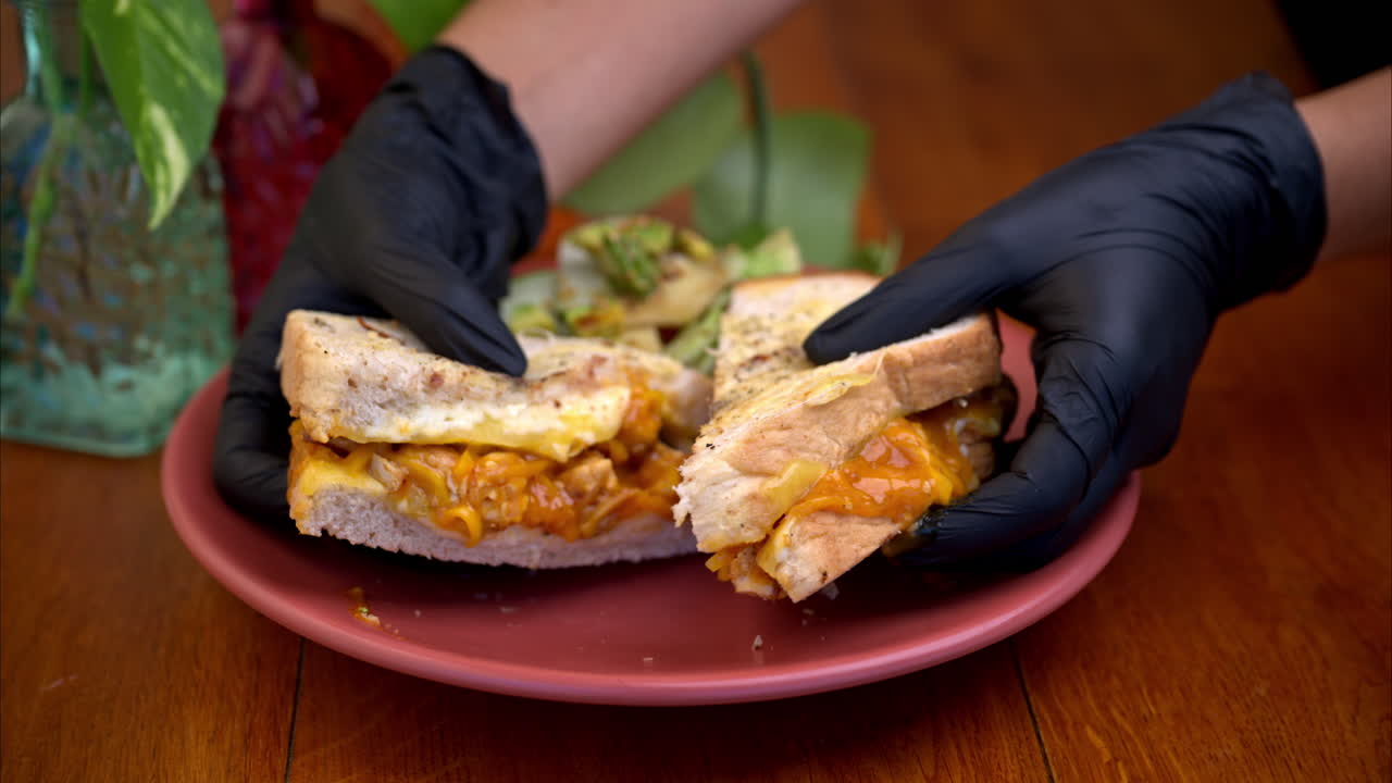 movimiento lento de una persona con guantes de látex negro sosteniendo y presentando un sándwich de pollo con salsa de mango en un restaurante en méxico