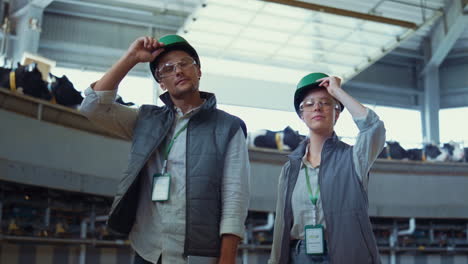 farmers posing dairy farm facility portrait. smiling workers taking off helmets.