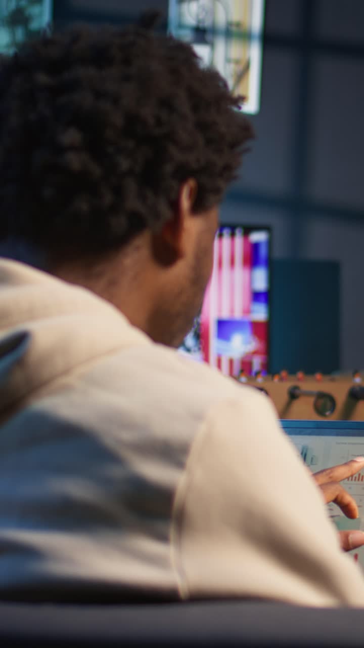 Uomo afroamericano che analizza i dati su un laptop in ufficio