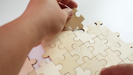 a person trying to solve a jigsaw puzzle without pictures, right hand holding the pieces in place while the right hand adds one piece after another