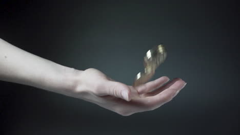 hand throwing and catching shiny bitcoin coins, black background