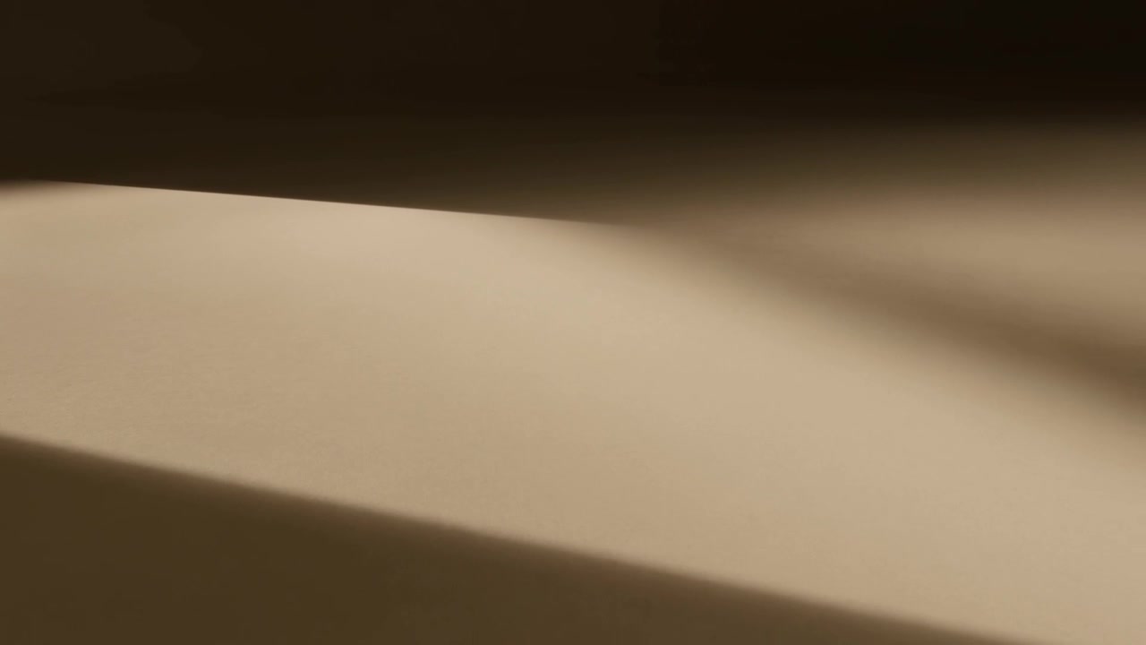Luce calda e angolata che si sposta crea un sottile riflesso su una superficie curva beige, mostrando lo spostamento della telecamera.