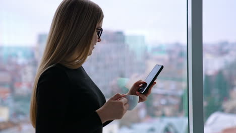 beautiful woman wearing eyeglasses using cellphone and drinking coffee