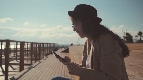 young woman using smartphone on the beach pier