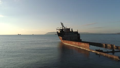 rusty shipwreck in the ocean at sunrise/sunset