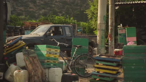 Old-bicycle-leans-against-shed-and-crates-with-old-truck-lit-by-afternoon-light,-Leonidio-Greece