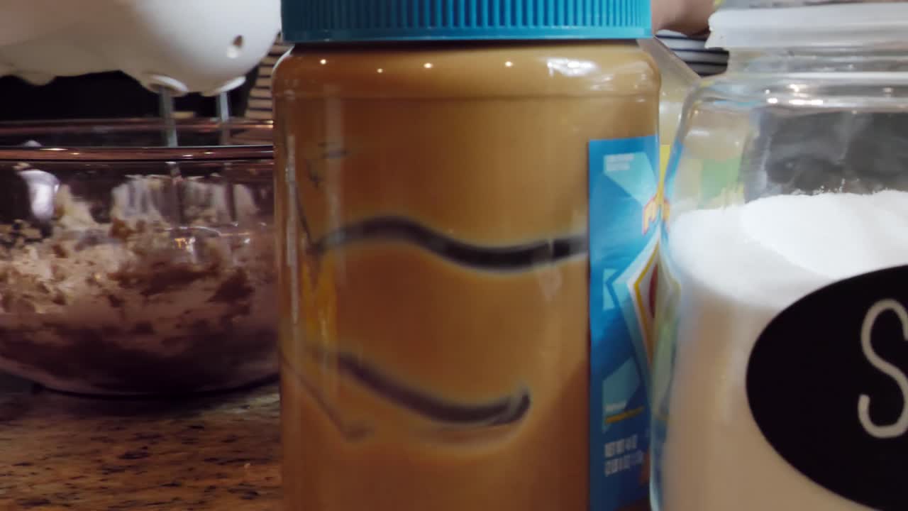 Electric whisk beating cookie dough in bowl, reveal behind ingredients