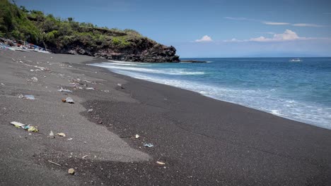 foamy waves washing ashore at the beach with toxic waste littered on the sand in bali, indonesia