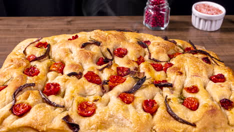 traditional italian focaccia with cherry tomatoes, black olives and rosemary