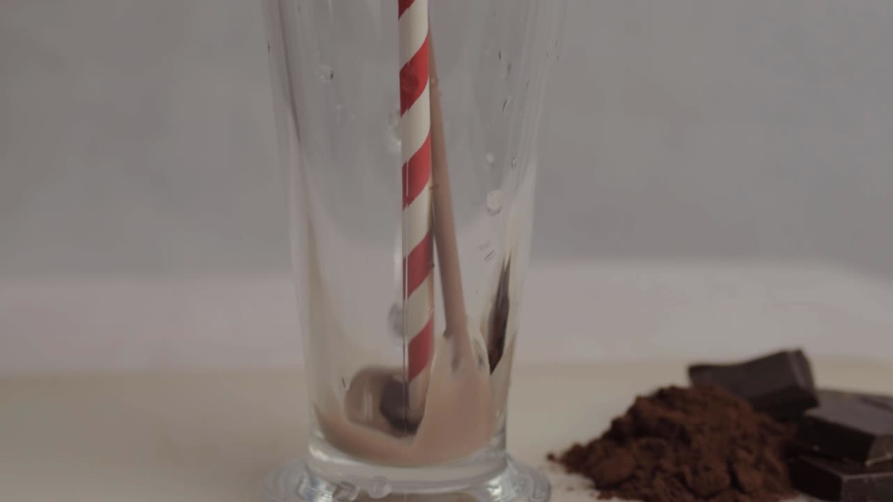 Versare un milkshake al cioccolato in un bicchiere con cannuccia, campo medio