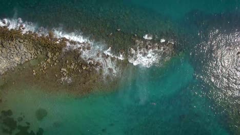 vista a volo d'uccello di un frangiflutti roccioso e onde che colpiscono contro di esso