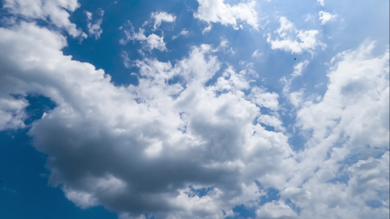 Beautiful light clouds flying in the sky. Sun rays going through the clouds in the bright blue skies. Low angle timelapse.