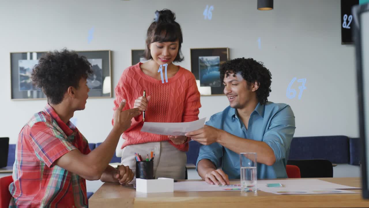 Man lifting white box, showing woman in red sweater as team reviewing sheets in business teamwork