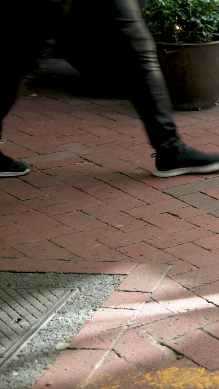 Vertical video: Entering first foot starting passersby crossing at entrance by planter, copy space
