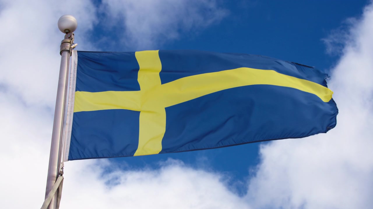 Bandeira da Suécia tremulando ao vento contra o céu azul.