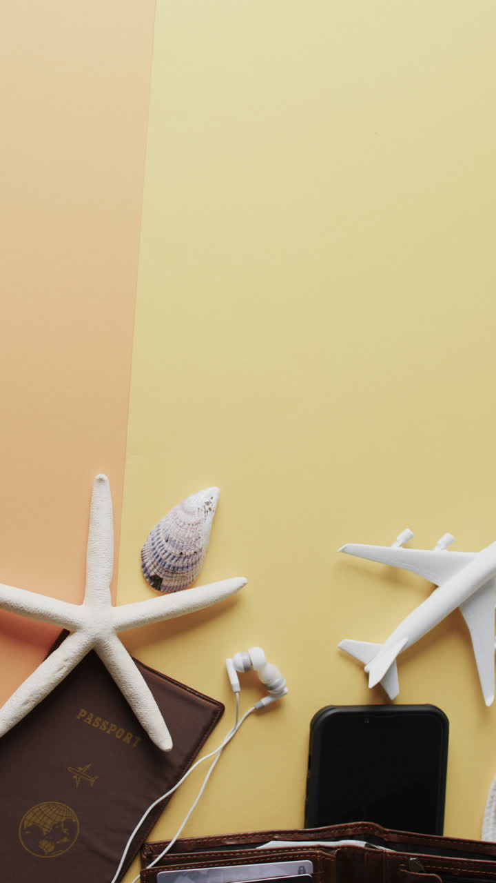 Vertical video of airplane model, shells, passport, smartphone and copy space on yellow background