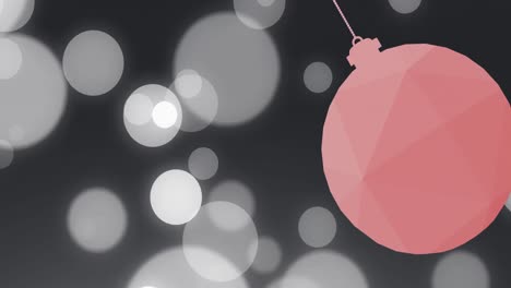 Animation-of-christmas-pink-bauble-over-white-spots-on-black-background