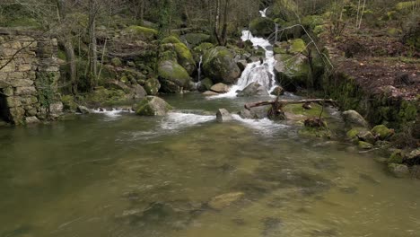 Tranquil-river-flow-and-old-stone-wall-in-Barrias,-Felgueiras-Portugal---aerial-flyover