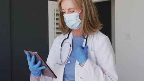 Doctora-Caucásica-De-Alto-Rango-Con-Guantes-Quirúrgicos-Y-Mascarilla-Facial-Usando-Una-Tableta