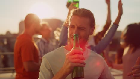 close up view of cheerful guy drinking beer in rooftop terrace