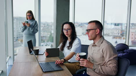 diverse colleagues discuss the topic on the laptop. female employee is focused on the phone at backdrop.