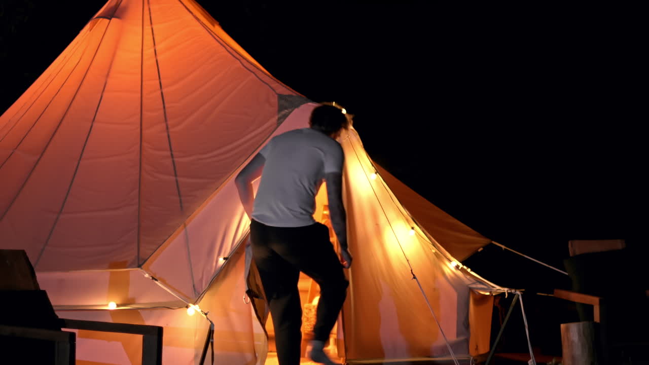 Couple entering a tent with nightlights. Glamping at night. Slow motion