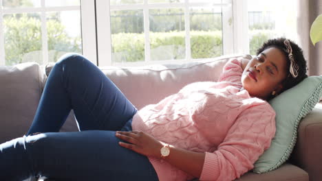 African-American-woman-relaxing-on-a-couch-at-home,-eyes-closed