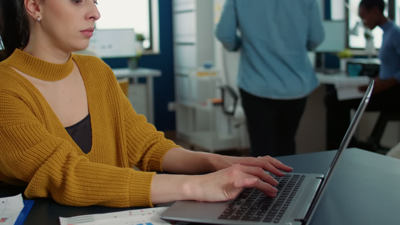 retrato de una mujer escribiendo usando el teclado de una computadora portátil y sonriendo a la cámara sentada en un escritorio
