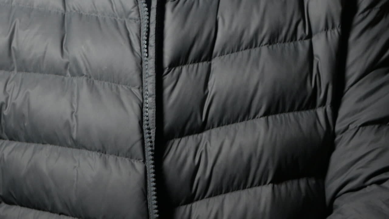 중년 백인 남성은 회색 푸퍼 재킷을 입고 지퍼를 올립니다