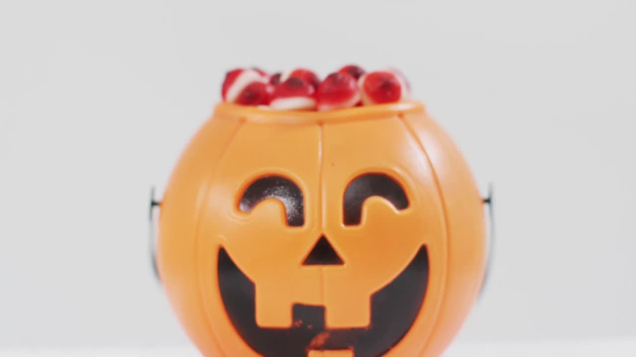 espeluznante calabaza de halloween cubeta impresa llena de dulces contra un fondo gris