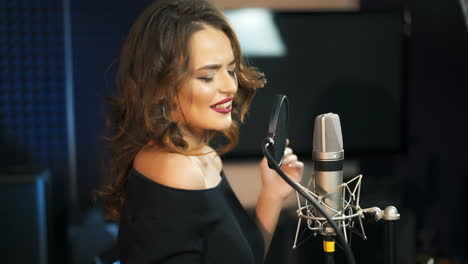 young female singer recording album in the professional studio. woman singing a song in music recording studio.
