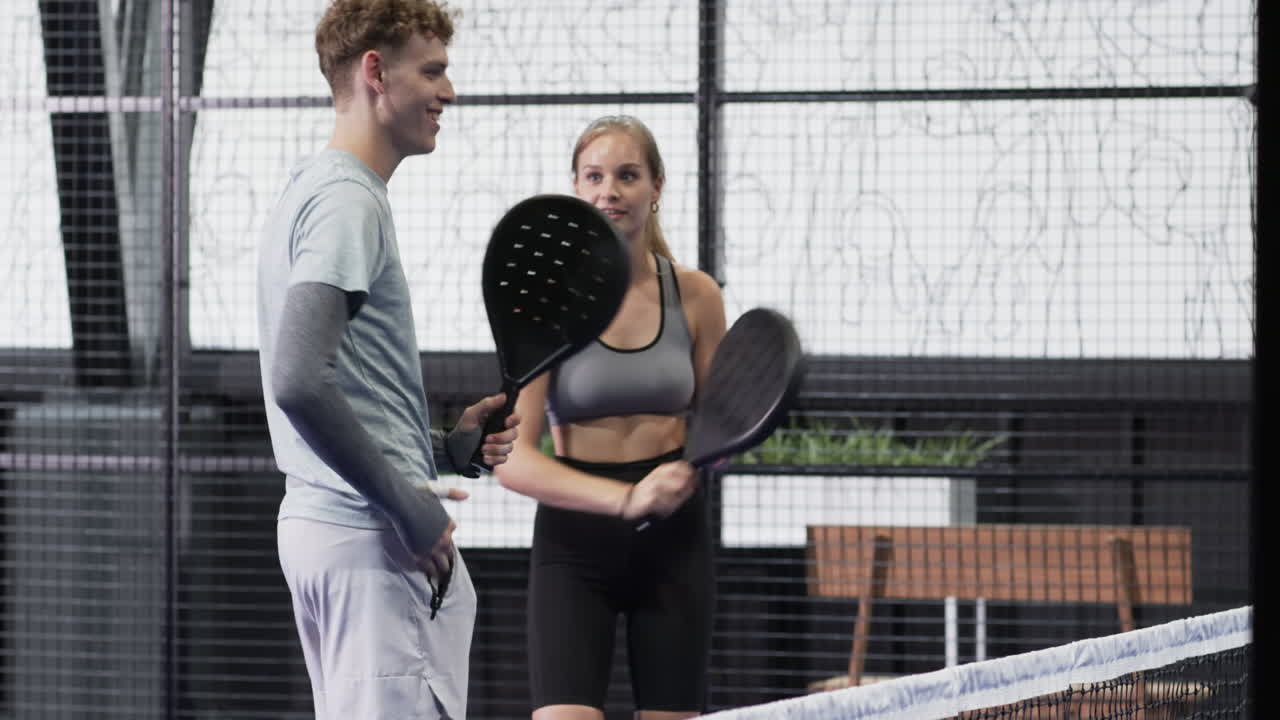 Playing padel tennis, young man and woman enjoying competitive match on indoor court