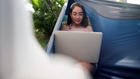woman working on a laptop in a hammock