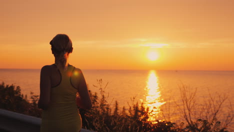 active and healthy lifestyle - woman silhouette running along the road along the sea at sunset