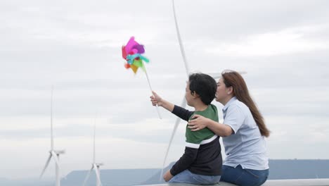 progressive happy mother and her son at the wind turbine farm.