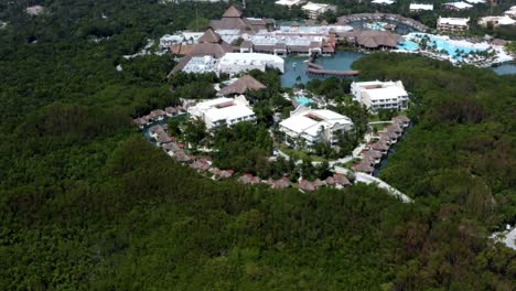 beautiful spinning aerial drone shot of a group of bungalows and larger buildings surrounded by a mangrove forest in a tropical vacation resort in riviera maya, mexico near mexico