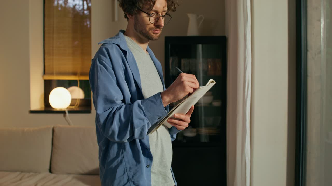 Man Writing in a Notebook at Home