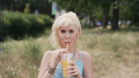 retrato en cámara lenta de una feliz y hermosa mujer caucásica bebiendo jugo