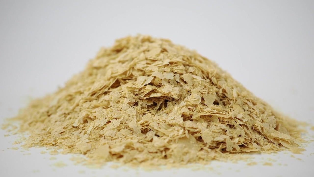 Un mucchio di fiocchi di lievito alimentare su uno sfondo bianco.